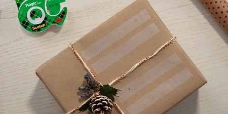 Creando etiquetas de regalo usando Cinta Scotch® Magic™ en un regalo envuelto

