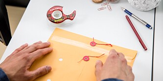Hombre sellando un sobre con cinta Scotch® Super-Hold
