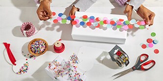 Envolviendo una caja de regalo con cinta de confeti hecha pegando confeti colorido a la cinta adhesiva Scotch®
