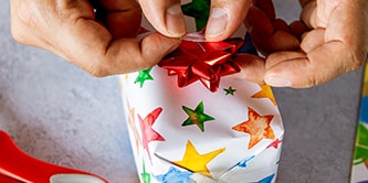 Usar papel de empaquetado estrellado y terminar el aspecto del envoltorio de regalo con una estrella de cinta en la parte superior
