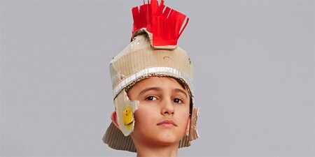 Un niño con un casco de Roman de cartón
