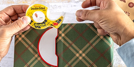 Adherir decoraciones a un regalo envuelto usando Cinta de Doble Cara Scotch®
