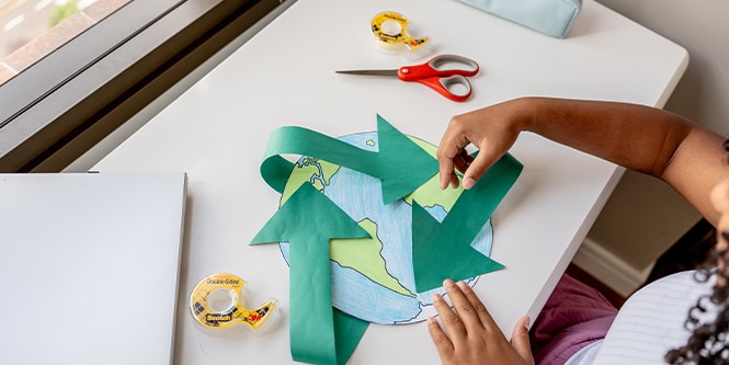 Niña creando un mapa mundial hecho de papel con suministros de la marca Scotch™
