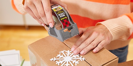 Sellar un regalo navideño dentro de un paquete usando Cinta Box Lock™ Scotch®
