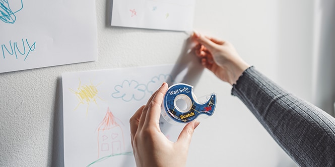 Colgando arte infantil en una pared usando Cinta Wall-Safe Scotch®
