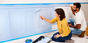 Pareja joven pintando la pared y utilizando cinta de enmascarar Scotch®

