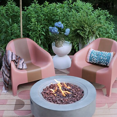 Patio al aire libre con una terraza pintada y una moderna fogata circular en el medio.