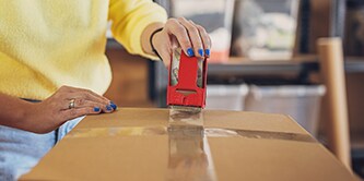 Mujer sellando una caja con cinta de embalaje Scotch®
