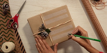 Crear etiquetas de regalo usando Cinta Scotch® Magic™ en un regalo envuelto con papel de empaquetado liso
